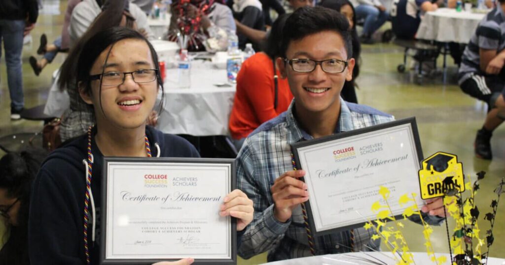 A student holding a scholarship certificate proudly